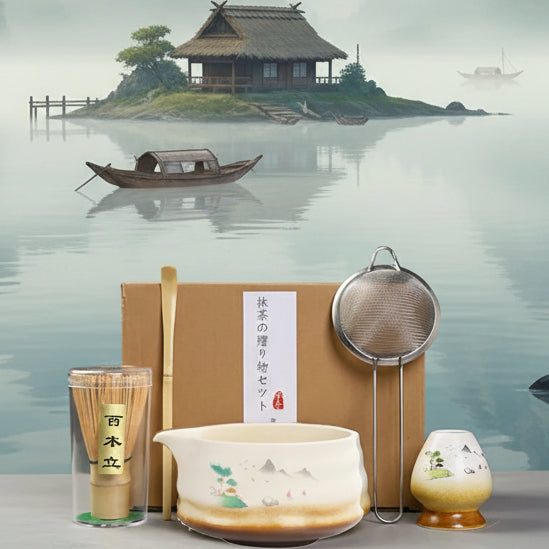 Tea-making set with a box, bowl, whisk, and other tools on a gray surface.