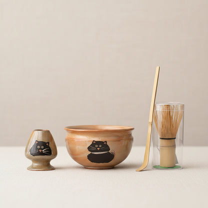 Tea set with a bowl, spoon, and other items on a dark surface.