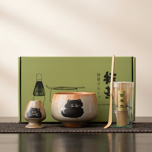 Tea set with cat design in front of a green box