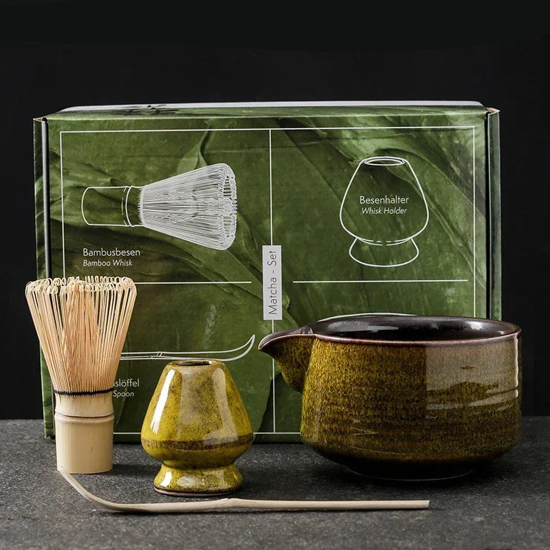 Tea-making set with green box, whisk, and teapots on a dark surface