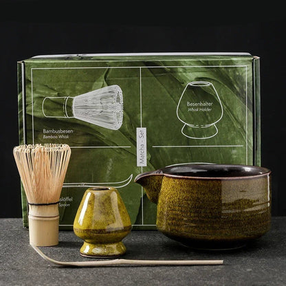 Tea-making set with green box, whisk, and teapots on a dark surface