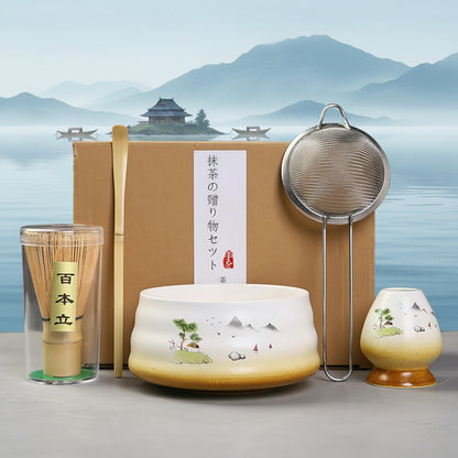 Tea-making set with a ceramic pot, whisk, and other tools on a gray surface.